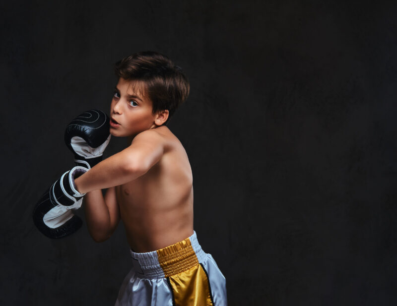 Handsome shirtless young boxer during boxing exercises, focused on process with serious concentrated facial.